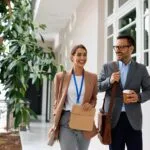 Happy business colleagues walking in hallway while coming to work.